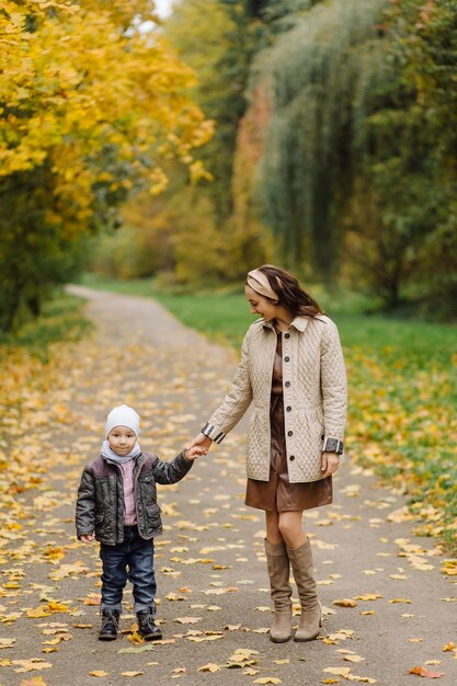 Mamá e hijo caminando y divirtiéndose juntos en el parque de otoño.