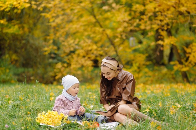 Mamá e hijo caminando y divirtiéndose juntos en el parque de otoño.