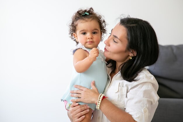 Mamá feliz con dulce hija en brazos. Niña linda a. Copie el espacio. Concepto de paternidad e infancia