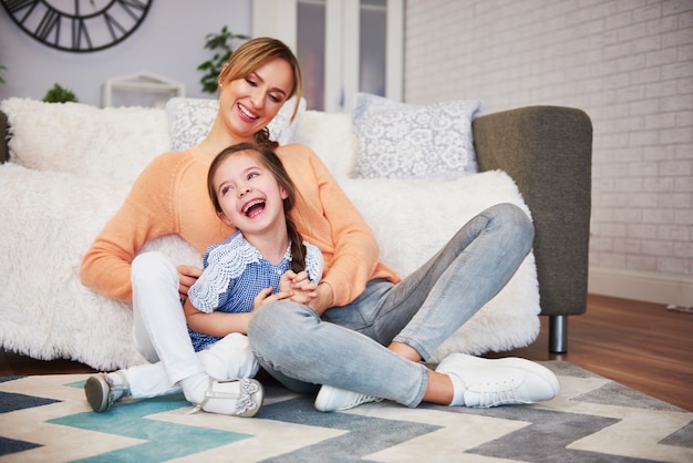 Mamá feliz y su pequeña hija divirtiéndose en casa