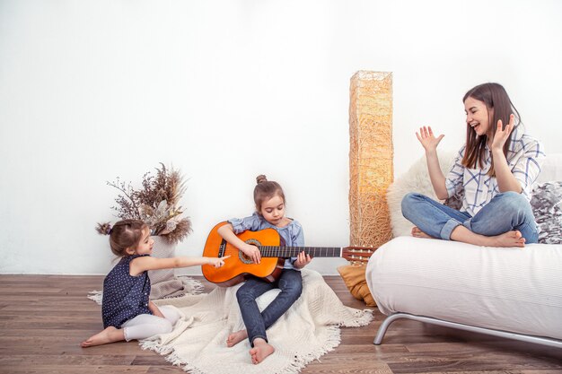 Mamá juega con sus hijas en casa. Lecciones de instrumentos musicales