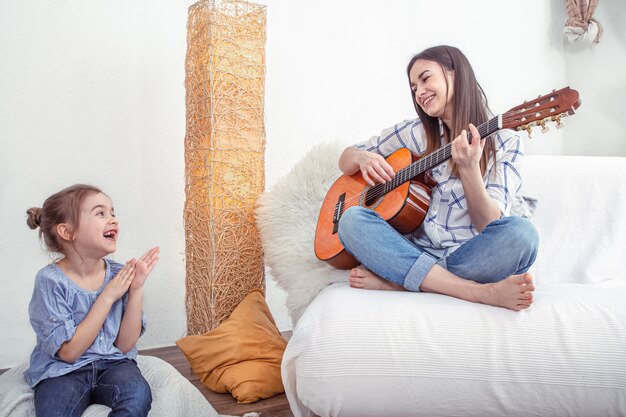 Mamá juega con sus hijas en casa. Lecciones de instrumentos musicales