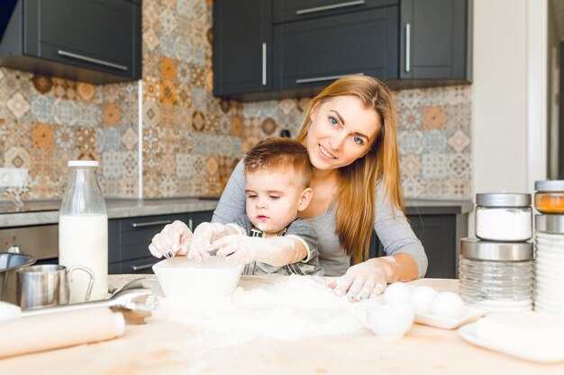 Mamá jugando con niño en la cocina. La cocina está hecha en colores oscuros y estilo rústico.