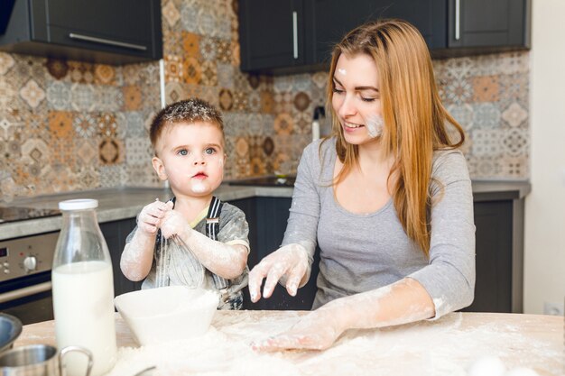 Mamá jugando con niño en la cocina. La cocina está hecha en colores oscuros y estilo rústico.