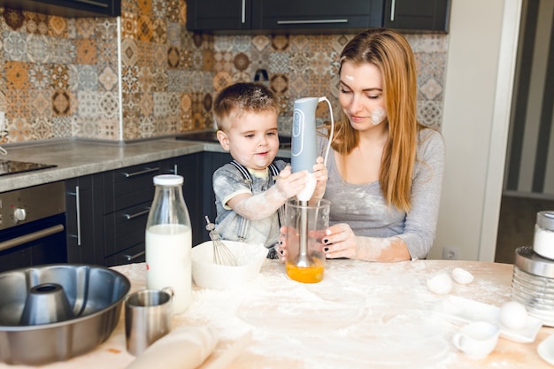 Mamá jugando con niño en la cocina. La cocina está hecha en colores oscuros y estilo rústico.