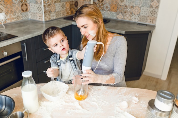 Mamá jugando con niño en la cocina. La cocina está hecha en colores oscuros y estilo rústico.