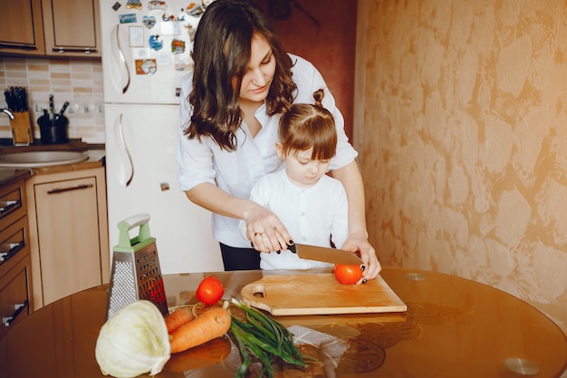 Mamá junto con su hija cocina verduras en casa en la cocina