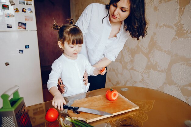 Mamá junto con su hija cocina verduras en casa en la cocina
