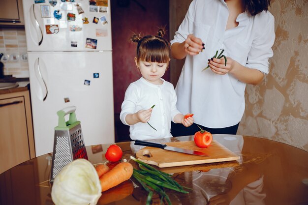 Mamá junto con su hija cocina verduras en casa en la cocina