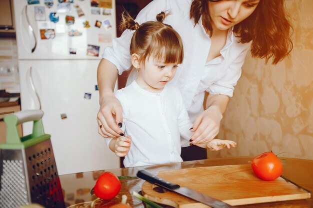 Mamá junto con su hija cocina verduras en casa en la cocina