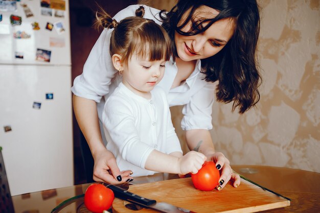 Mamá junto con su hija cocina verduras en casa en la cocina