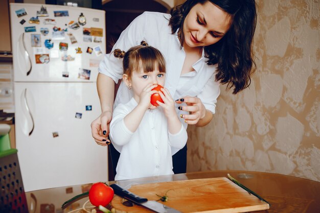 Mamá junto con su hija cocina verduras en casa en la cocina