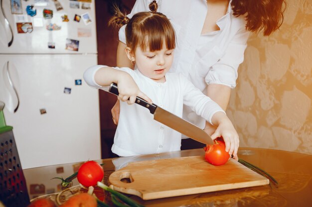 Mamá junto con su hija cocina verduras en casa en la cocina