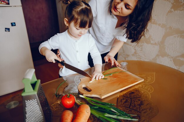 Mamá junto con su hija cocina verduras en casa en la cocina