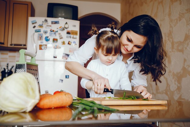 Mamá junto con su hija cocina verduras en casa en la cocina