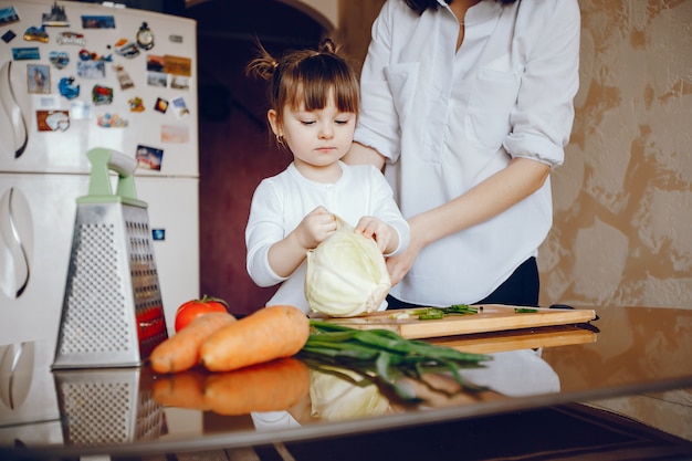 Mamá junto con su hija cocina verduras en casa en la cocina