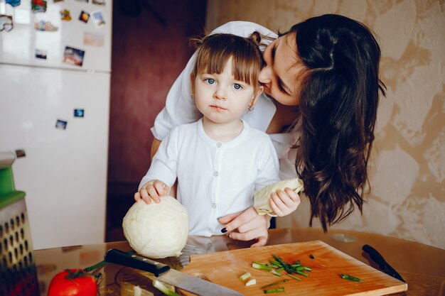 Mamá junto con su hija cocina verduras en casa en la cocina