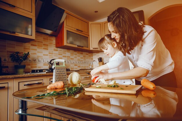 Mamá junto con su hija cocina verduras en casa en la cocina