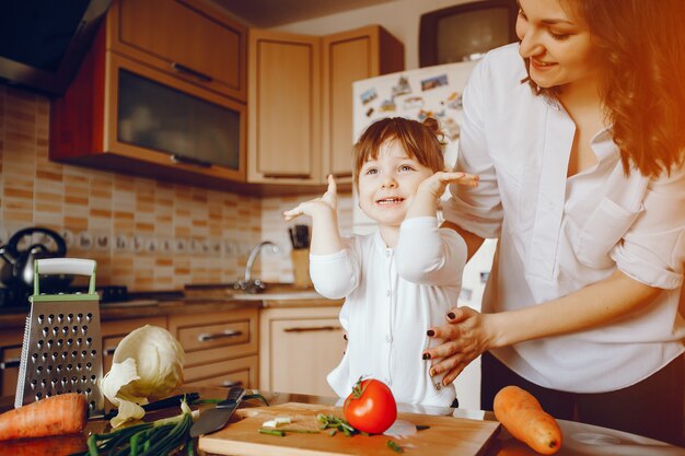 Mamá junto con su hija cocina verduras en casa en la cocina