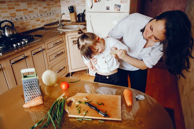 Mamá junto con su hija cocina verduras en casa en la cocina