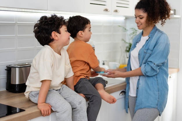 Mamá lavando platos con sus hijos