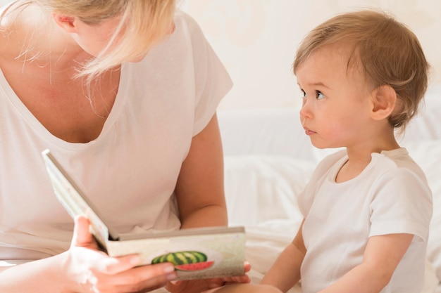 Foto gratuita mamá leyendo al bebé en la cama