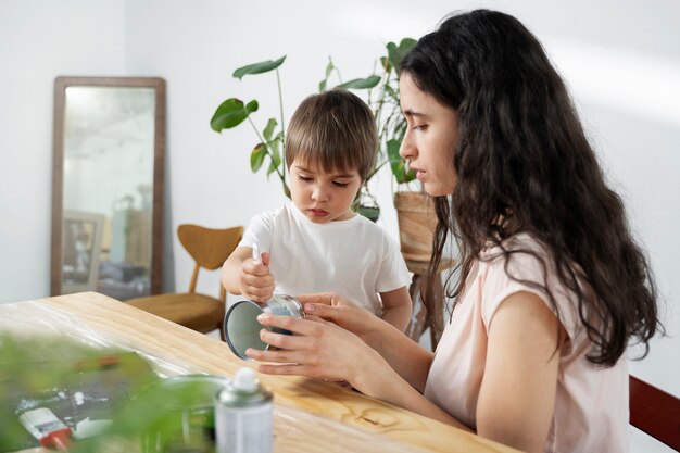 Mamá le muestra a un niño cómo reutilizar materiales de manera creativa