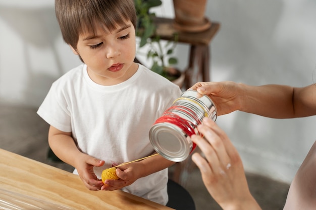 Mamá le muestra a un niño cómo reutilizar materiales de manera creativa