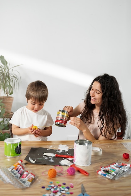 Foto gratuita mamá le muestra a un niño cómo reutilizar materiales de manera creativa