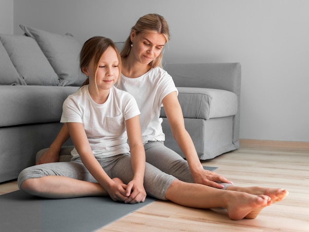 Foto gratuita mamá y niña en estera estiramiento