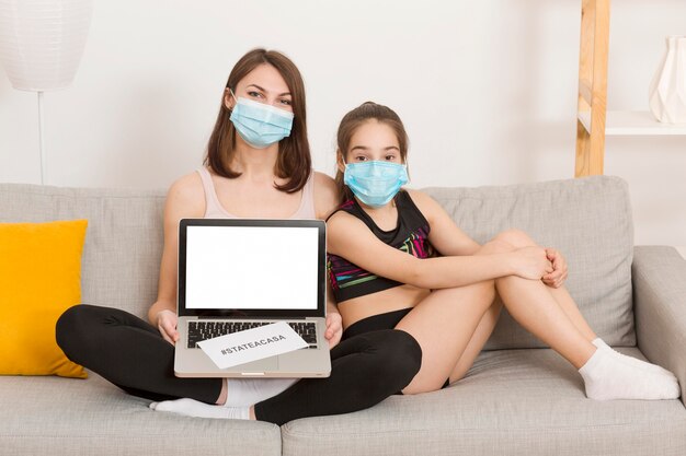 Mamá y niña en el sofá con laptop