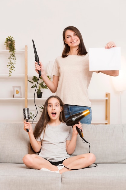 Mamá ondulante cabello de niña en casa