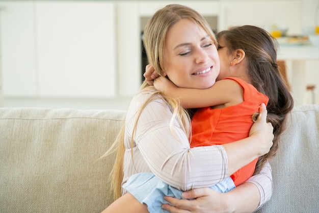 Mamá pacífica sosteniendo a su pequeña niña en brazos en su regazo y abrazándola.