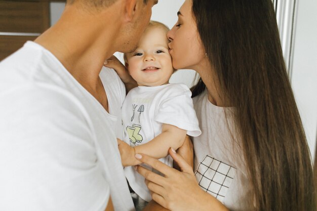 Mamá y papá besan a su pequeño hijo. El niño se está regocijando.