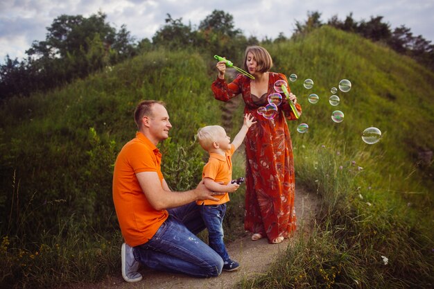 Mamá y papá soplan globos de jabón con su hijo