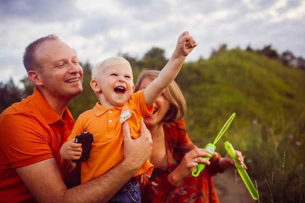 Foto gratuita mamá y papá soplan globos de jabón con su hijo