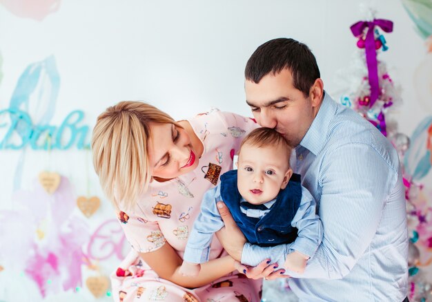 Mamá, papá y su pequeño hijo posan en la habitación con el árbol de Navidad rosa