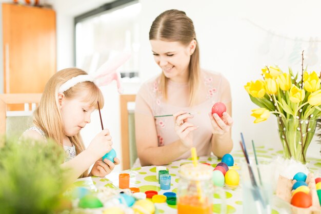 Mamá pintando huevos de Pascua con hija