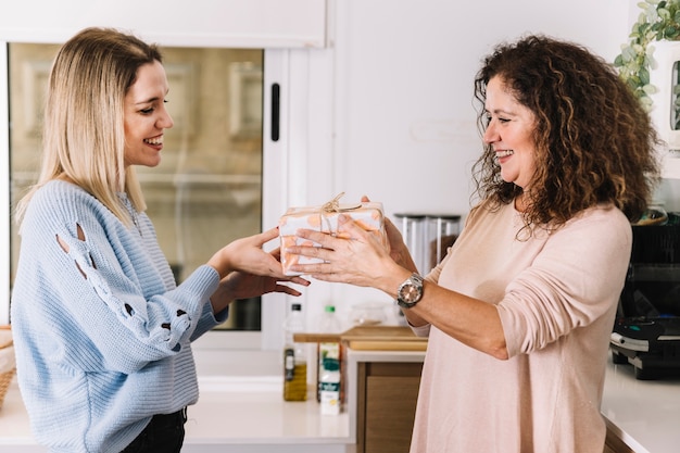 Foto gratuita mamá recibe un regalo de la hija en la cocina