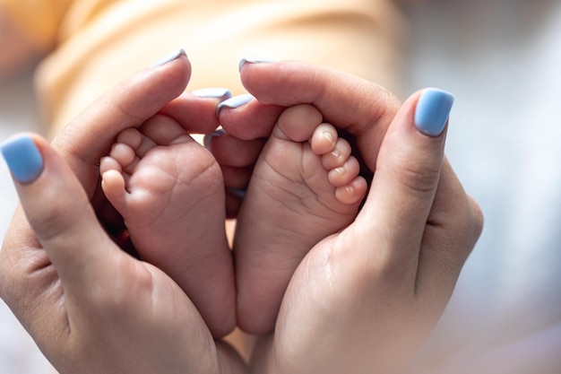 Foto gratuita mamá sostiene las piernas de un bebé recién nacido en sus manos