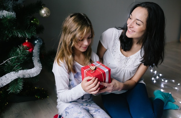 Mamá y su niña linda hija intercambiando regalos.