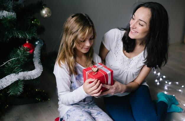 Mamá y su niña linda hija intercambiando regalos.