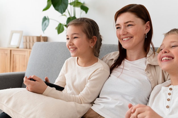 Mamá viendo la televisión con sus hijos.