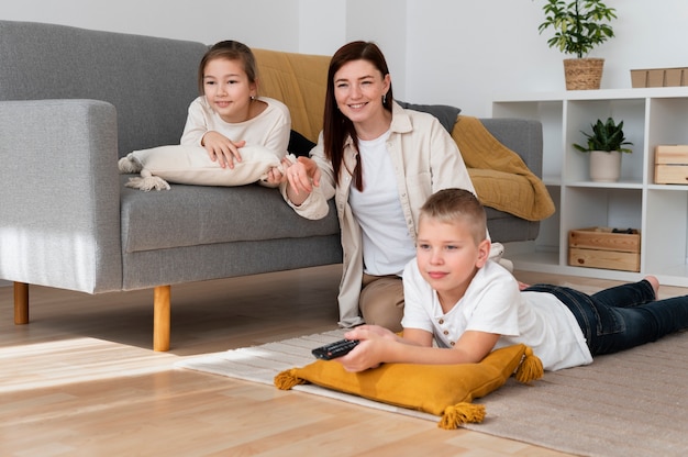 Mamá viendo la televisión con sus hijos.