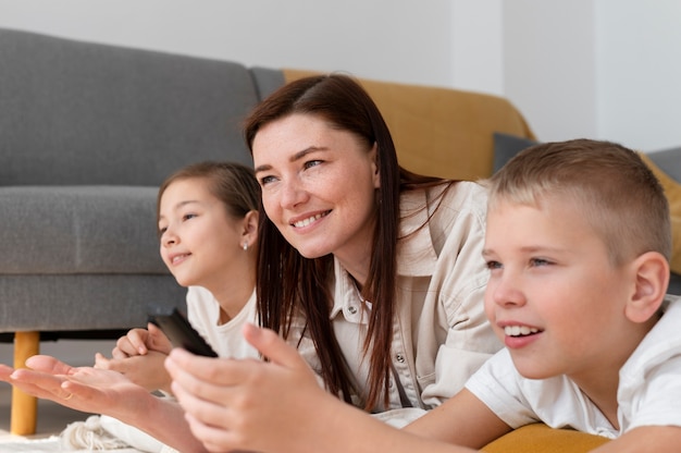 Mamá viendo la televisión con sus hijos.