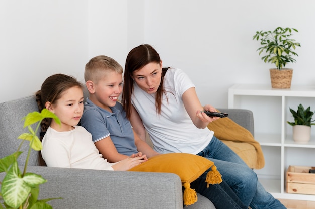 Mamá viendo la televisión con sus hijos.