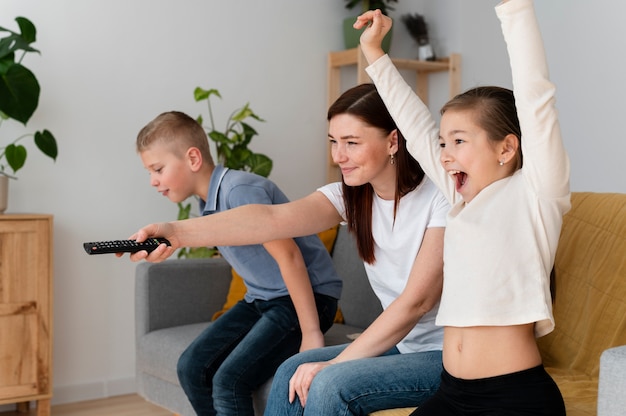 Mamá viendo la televisión con sus hijos.