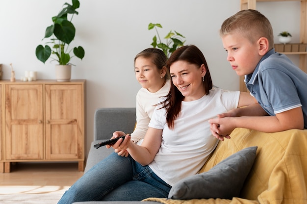 Mamá viendo la televisión con sus hijos.