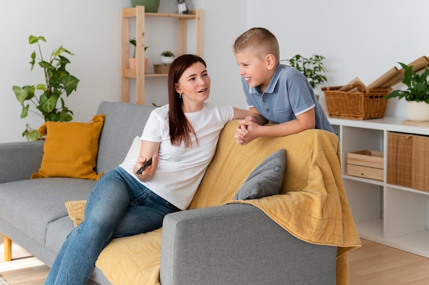 Mamá viendo la televisión con sus hijos.