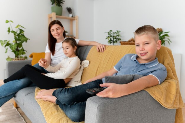 Mamá viendo la televisión con sus hijos.